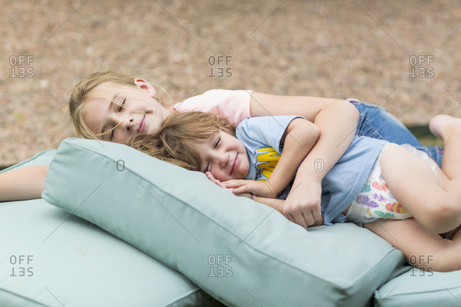 Children napping outside on a pile of cushions
