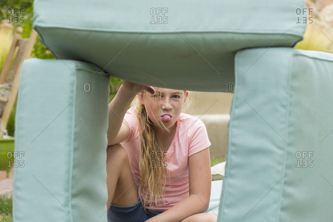 Girl sitting under a cushion fort sticking her tongue out
