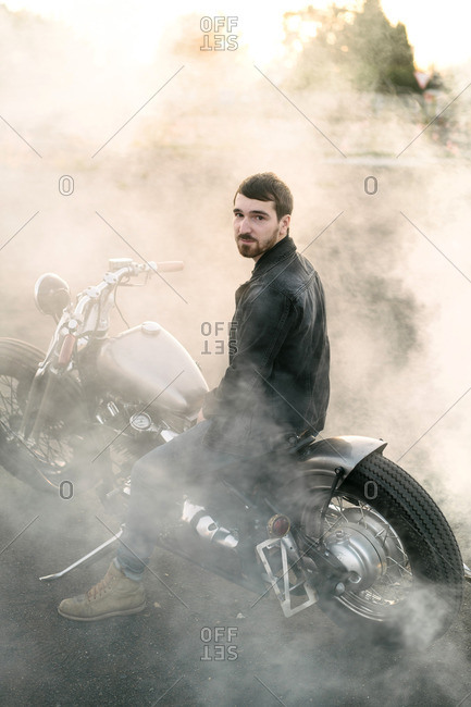Man sitting on a motorcycle surrounded by smoke