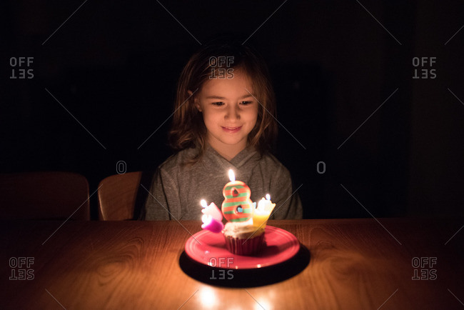 Girl celebrating her 8th birthday with a birthday cupcake