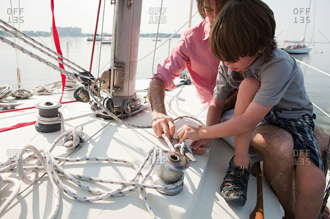 Father and son on board yacht tying a rope