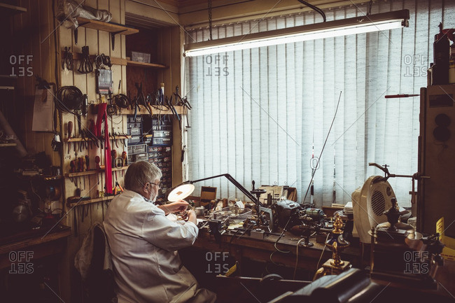 Rear view of horologist repairing an watch in the workshop