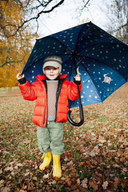 Boy in rain boots and umbrella in park
