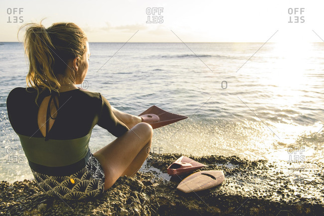 Woman putting on flippers by ocean