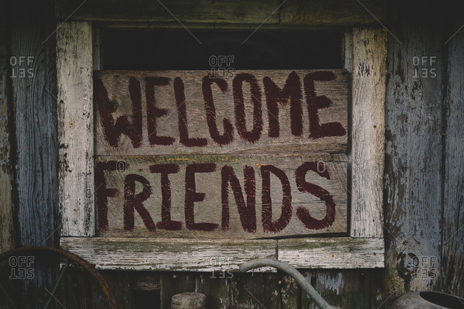 Wood sign with the words \'Welcome Friends\' in an old barn window