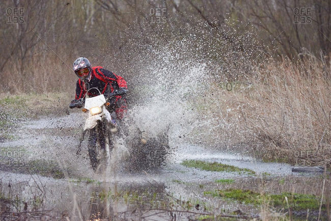 Motocross rider racing in flooded field