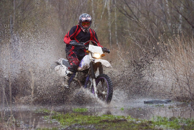 Motocross rider riding in flooded field