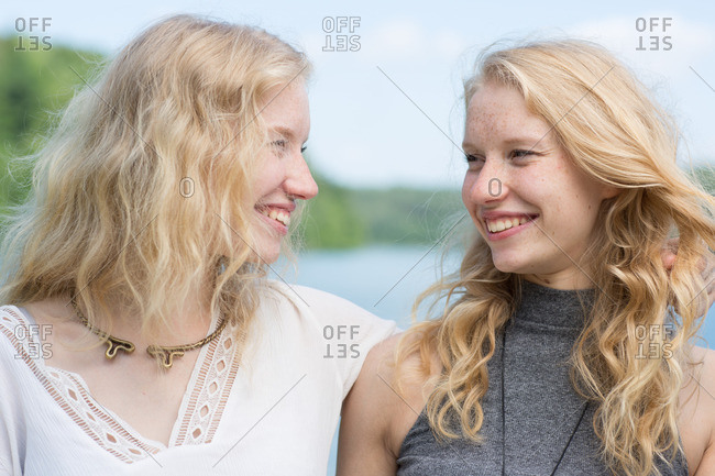 Two blonde twins standing face to face by a lake