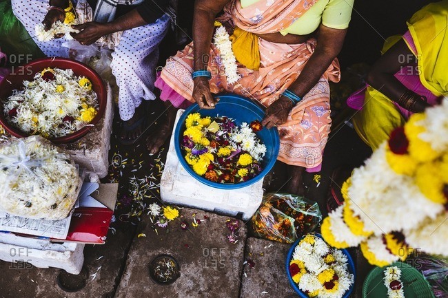 Women lace flowers on strings at the Margao market in southern Goa, India