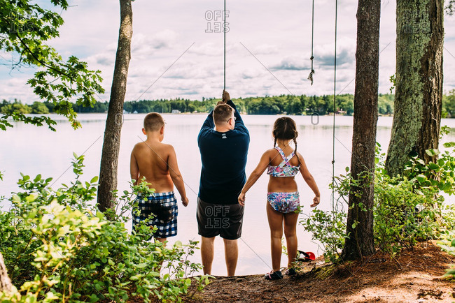 Family at lake rope swing