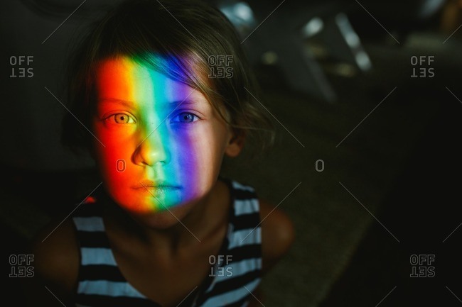 Young girl with a rainbow prism of light illuminating her face