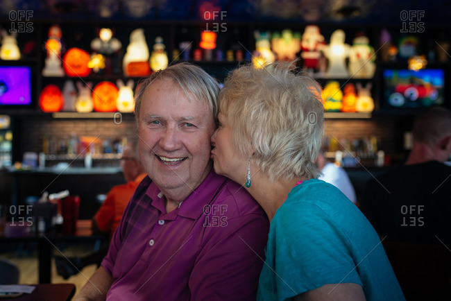 A middle-aged couple kissing each other in a bar