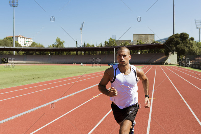 Young sportsman running on tartan track