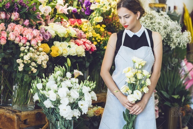 Female florist holding yellow roses in flower shop