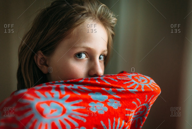 Child peeking over the edge of red fabric