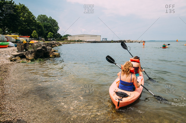 Two women in kayak launch off beach