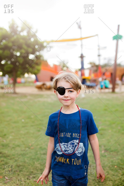 Young boy wearing eye patch and beaded necklace at park
