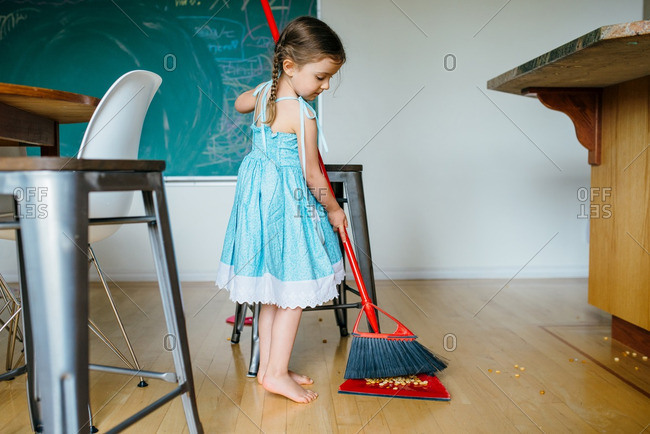 Little girl sweeping up spilled cereal