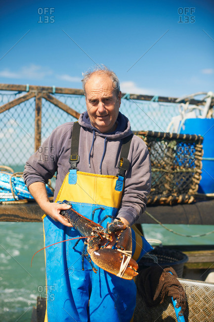 Fisherman holding lobster on boat