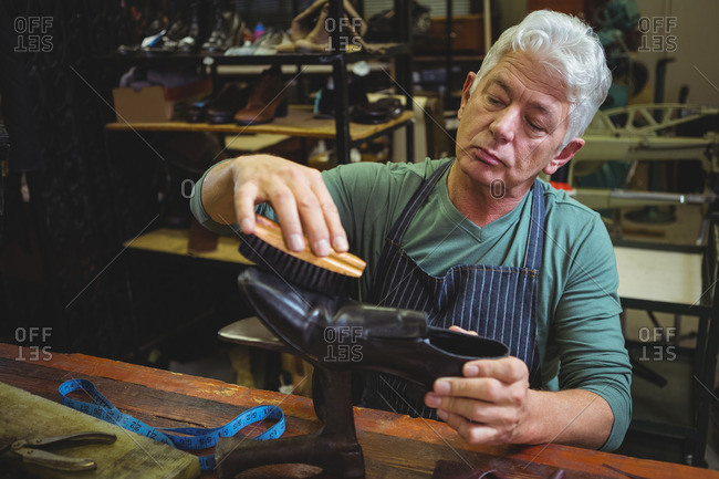 Shoemaker polishing a shoe in workshop