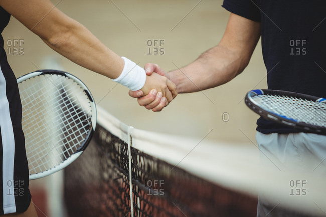 Mid section of tennis players shaking hands in the court before the match