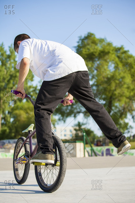 Young teenage kid on bmx bike in skate park performing tricks