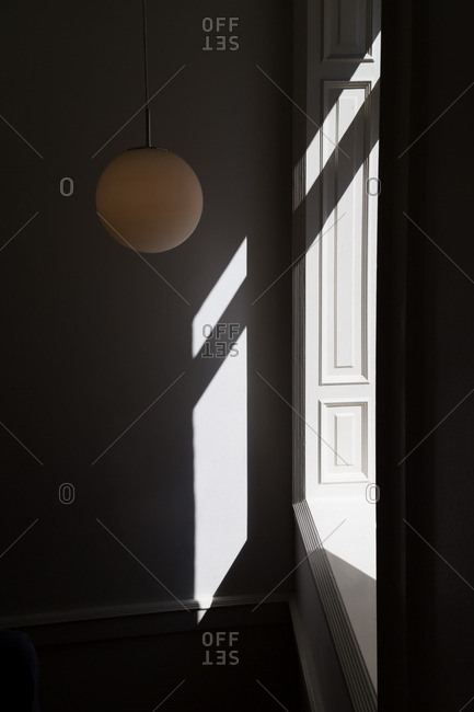 Round light fixture hanging near a sunlit window in a room