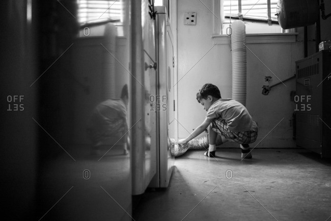 Boy inspecting a dryer exhaust pipe in a laundry room