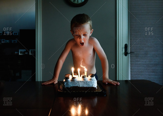 Young boy takes breath to blow out birthday candles