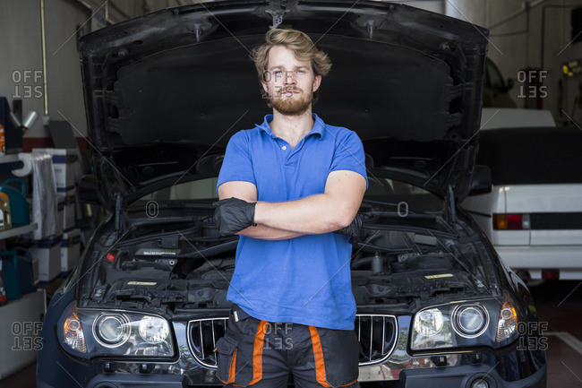 Mechanic standing in his car workshop with arms crossed