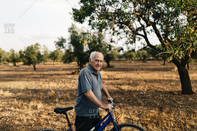 Senior man with bicycle on a field