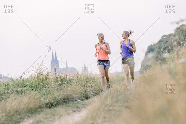 Two young women running on field path