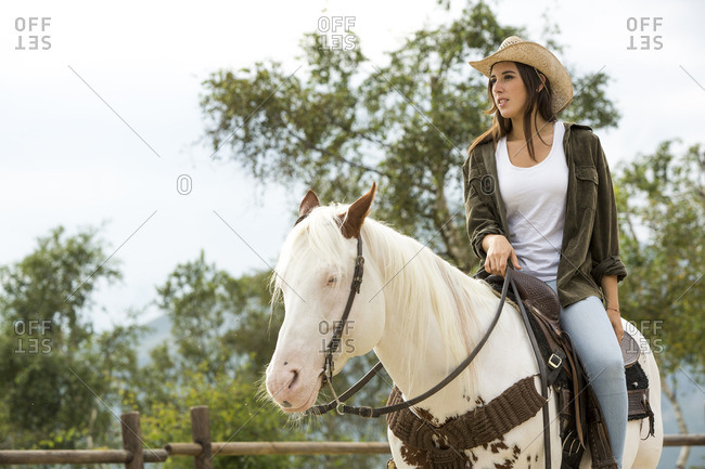 Young woman riding horse at riding stable