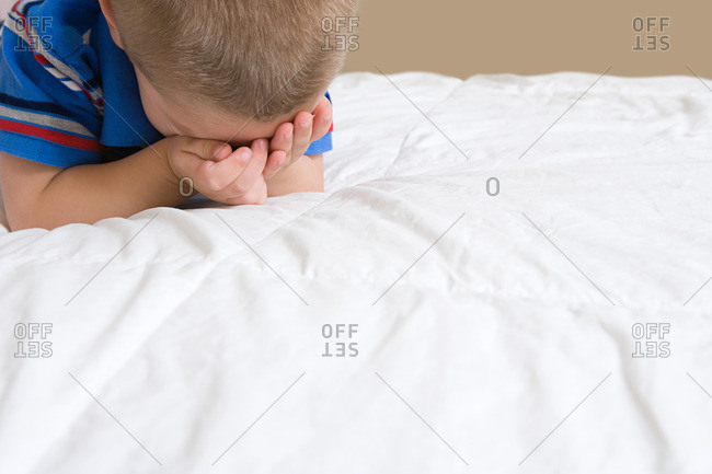 Little boy crying on bed