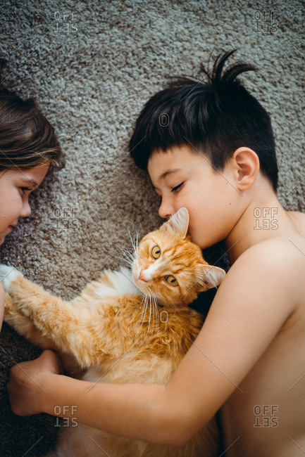 Two young children laying on floor with cat