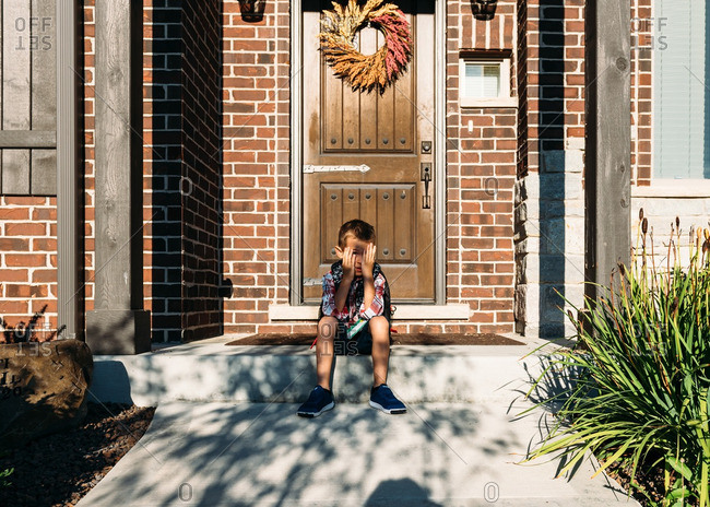 Boy blocking sun from face on first day of school