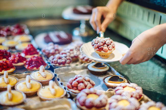 Woman\'s hands selecting fruit tart in cake shop, Florence, Italy