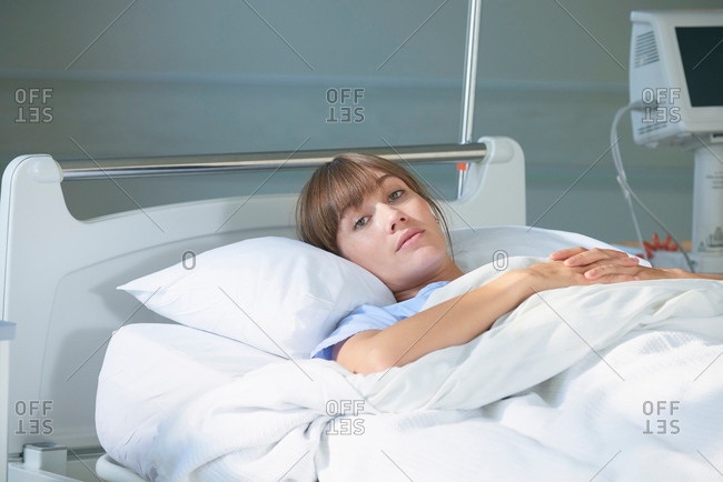 Woman lying on hospital bed looking at camera