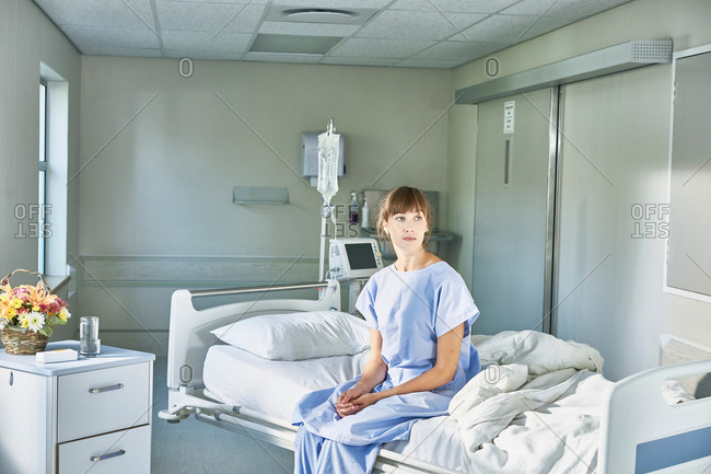 Patient sitting on hospital bed wearing hospital gown