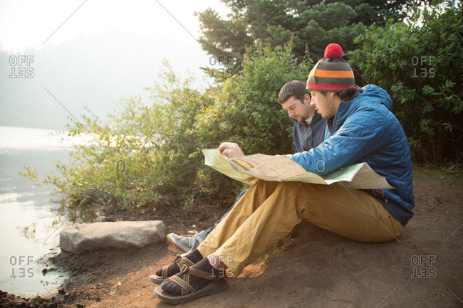 Two young male hikers reading map by lake, Mount Hood National Forest, Oregon, USA