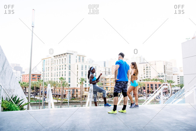 Man and two young women training, chatting on stairway at sport facility, downtown San Diego, California, USA