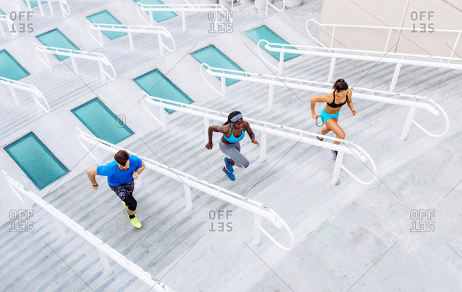 High angle view of man and two women training, running up stairway at sport facility, downtown San Diego, California, USA
