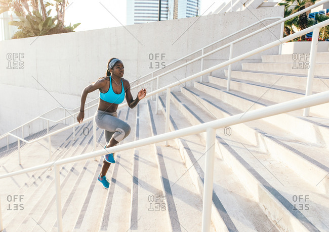 Young woman training, running up sport facility stairway, downtown San Diego, California, USA