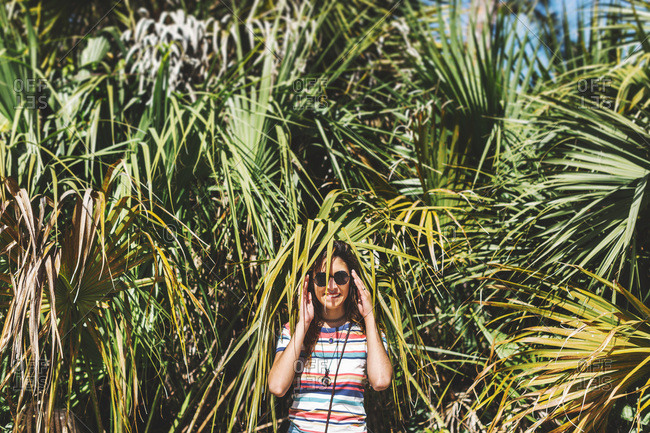 Woman hiding among palm fronds, Bonita Springs, Florida