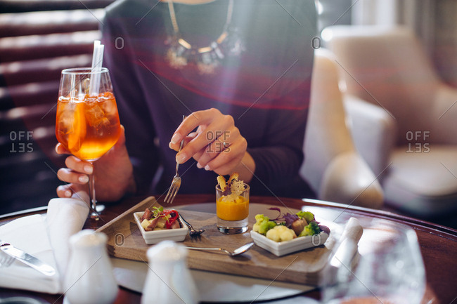 Cropped shot of young woman staying in boutique hotel eating aperitif