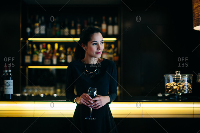 Sophisticated young woman staying in boutique hotel drinking champagne in cocktail bar