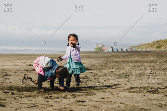 Two little girls playing in mud on a beach