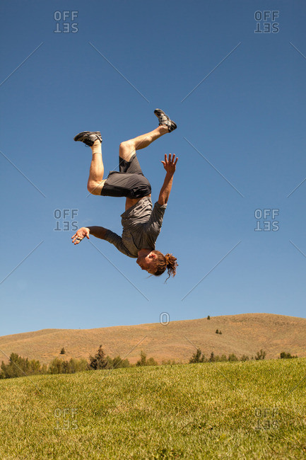 Athletic man doing back flip outdoors