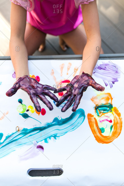Girl showing her messy hands while finger painting