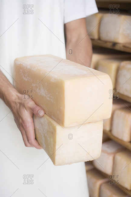 Man holding two blocks of cheese in a cheese dairy